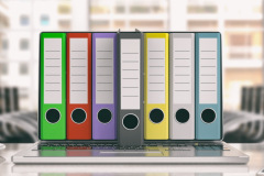 Colorful ring binders out of a laptop screen in an office. 3d illustration