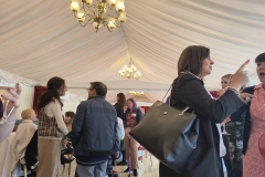 Room inside the House of Lords where the event was held. Attendees are gathered networking over lunch. The room has light fixtures on the right and left side above with a big white drape covering the ceiling.