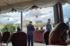 A few attendees are standing outside the room on the terrace with a view of the River Thames.