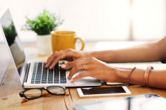 Cropped shot of an unrecognizable businesswoman sitting alone and typing on her laptop during the day at home